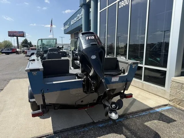 Slide: The Image of 2012 Lund 1750 Tyee boat with outboard motor, parked outside a dealership. - 3