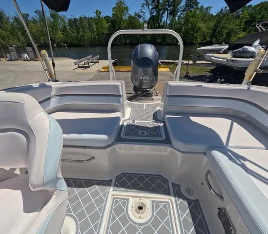 Slide: The Image of 2019 Chaparral 191 Suncoast boat interior with seating and outboard motor, docked by a river. - 17
