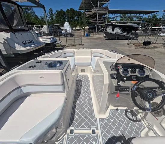 Slide: The Image of 2019 Chaparral 191 Suncoast boat interior with steering wheel, seating, and dashboard in a marina. - 29