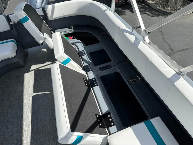 Slide: The Image of 2025 Aura Quad Lounge boat interior with open storage compartments and cushioned seating. - 25