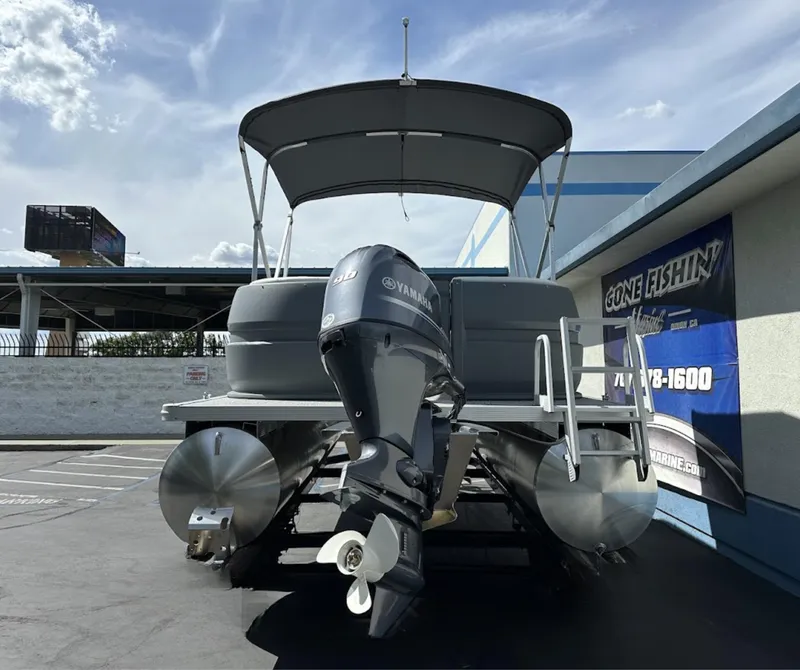 Slide: The Image of 2025 Aura Quad Lounge pontoon boat with Yamaha motor, parked outdoors under a clear sky. - 28