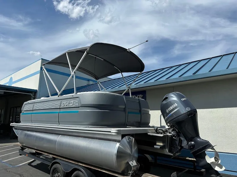 Slide: The Image of 2025 Aura Quad Lounge pontoon boat with Yamaha motor, parked outdoors under a blue sky. - 4
