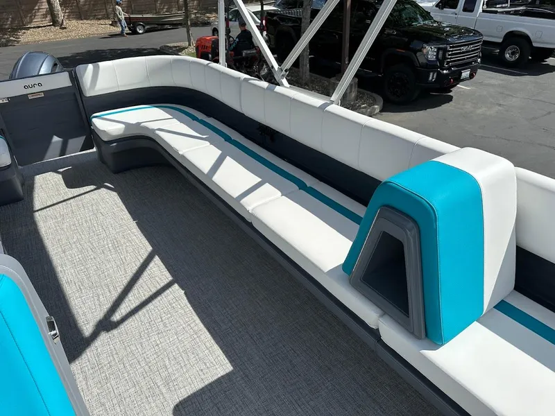Slide: The Image of 2025 Aura Quad Lounge boat interior with white and blue seating, outdoor setting. - 8