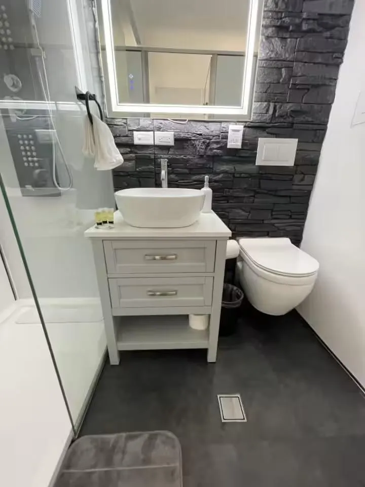 Slide: The Image of Modern bathroom with stone accent wall, sleek vanity, and illuminated mirror, featuring Modern Struktures MS 360. - 14