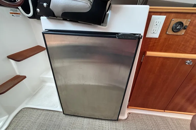 Slide: The Image of 2022 Cutwater C-248 Coupe interior with stainless steel fridge and wooden cabinetry. - 19