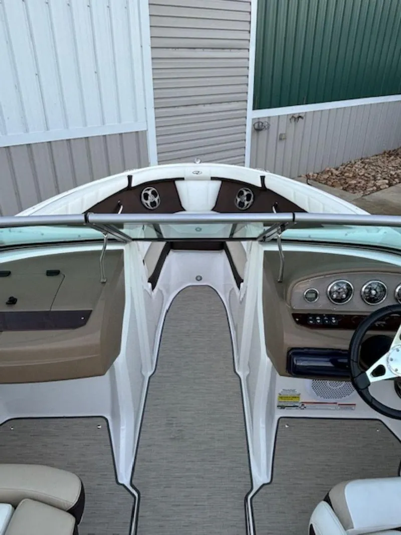 Slide: The Image of 2015 Regal 2000 ES boat interior with steering wheel and dashboard, docked near metal siding. - 15