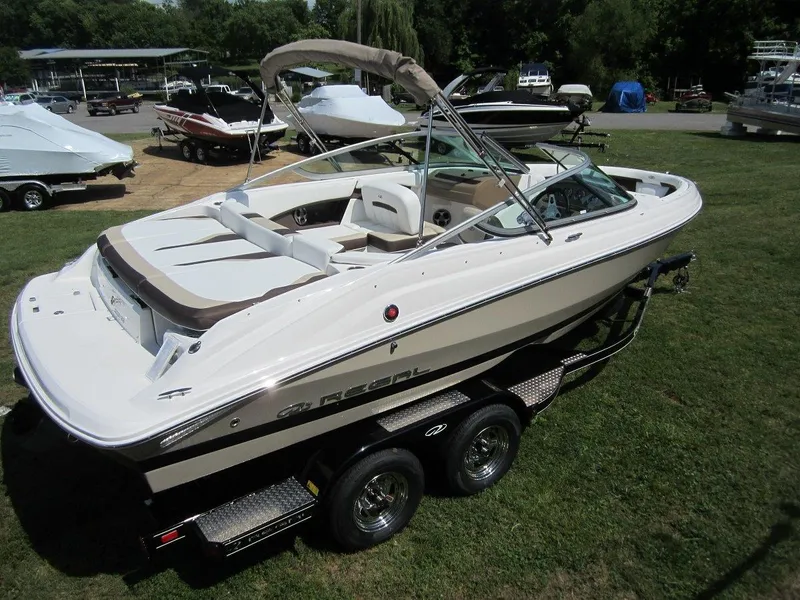 Slide: The Image of 2015 Regal 2000 ES boat on trailer, parked on grass, with other boats in background. - 32