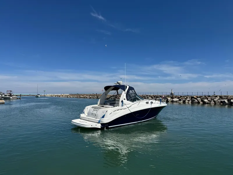 Slide: The Image of 2004 Sea Ray 320 Sundancer boat cruising in a calm harbor under a clear blue sky. - 11