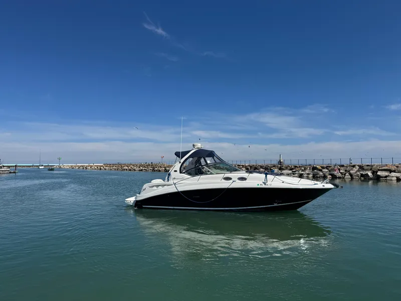 Slide: The Image of 2004 Sea Ray 320 Sundancer yacht cruising in a calm harbor under a clear blue sky. - 14