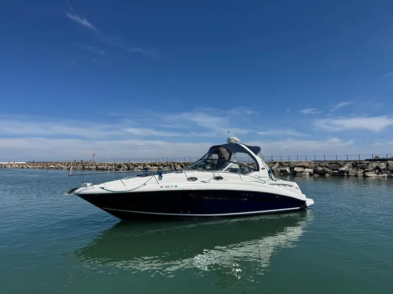 Slide: The Image of 2004 Sea Ray 320 Sundancer boat on calm water under clear blue sky. - 4