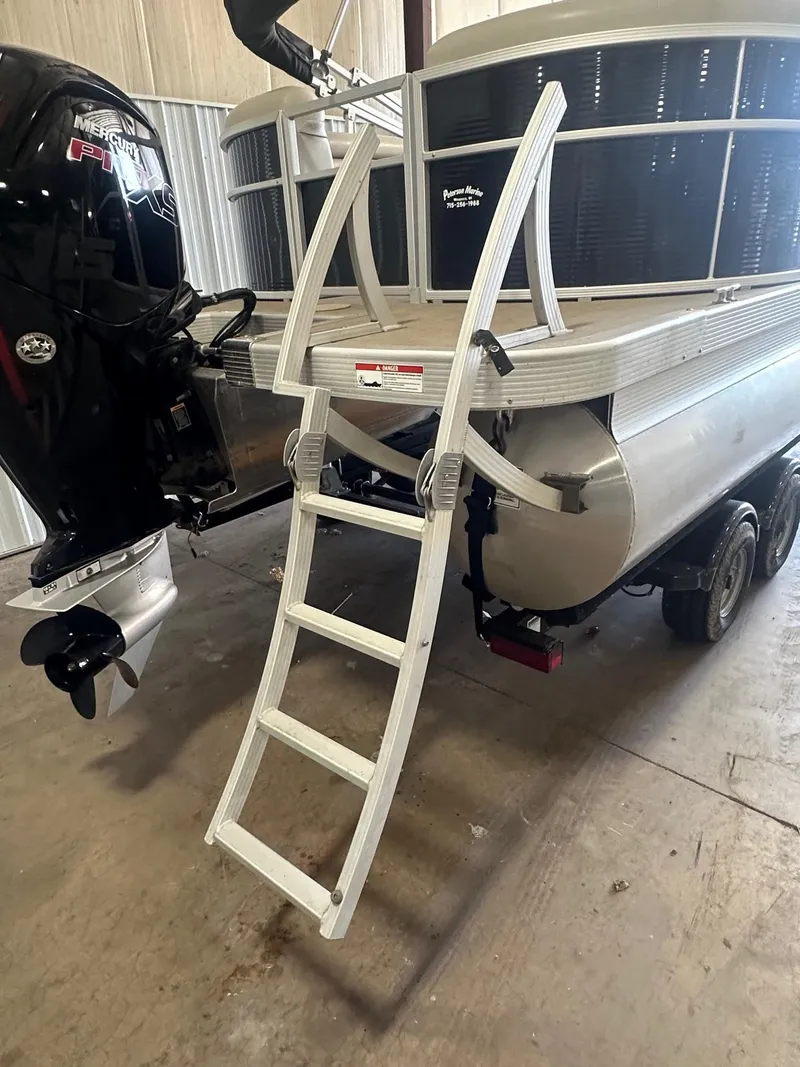 Slide: The Image of 2018 Bennington 21 SSRCX pontoon boat with ladder and Mercury outboard motor in a garage. - 5