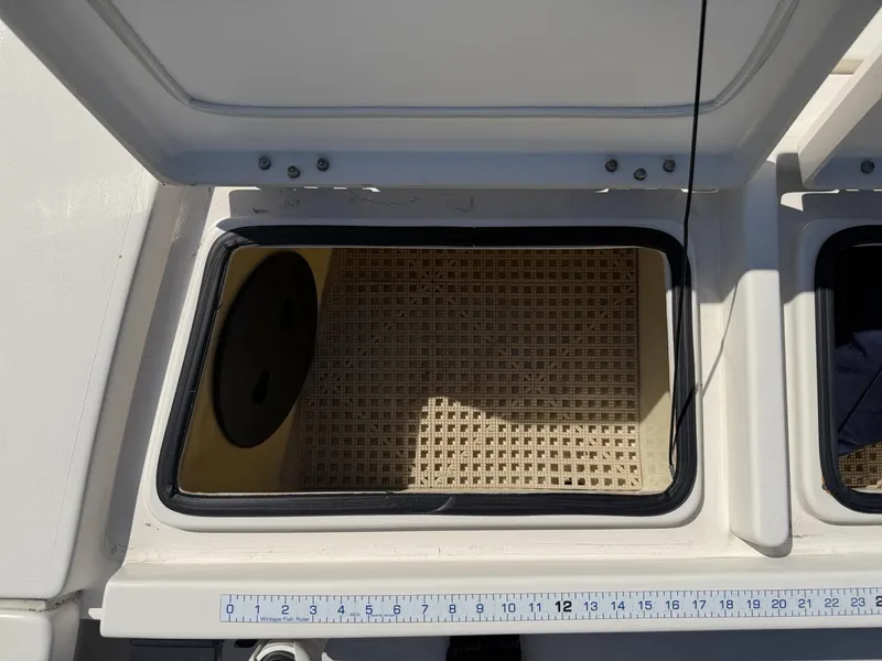 Slide: The Image of Open storage compartment on a 2009 Hewes 18 Redfisher boat with a fish ruler. - 26