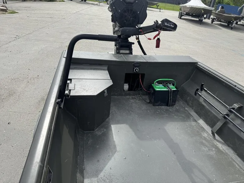 Slide: The Image of 2025 Gator Tail 1748 boat interior with motor and battery on concrete surface. - 13