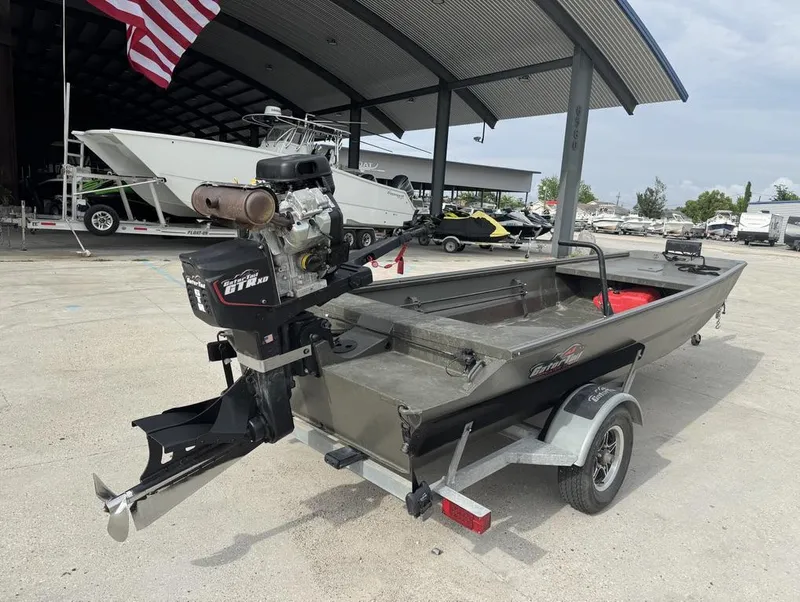 Slide: The Image of 2025 Gator Tail 1748 boat on trailer, parked under a metal canopy with American flag. - 7