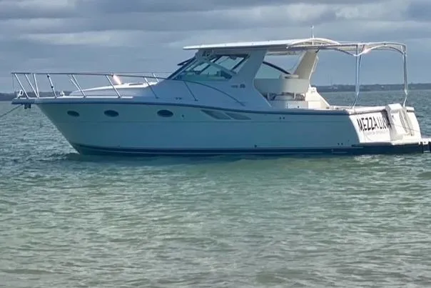 The Image of 1998 Tiara Yachts 3500 Open boat on calm water under cloudy sky. - 0