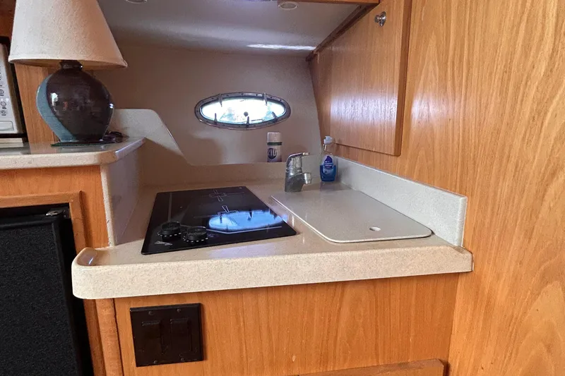 Slide: The Image of 1998 Tiara Yachts 3500 Open interior kitchen with stove, sink, and wooden cabinetry. - 11