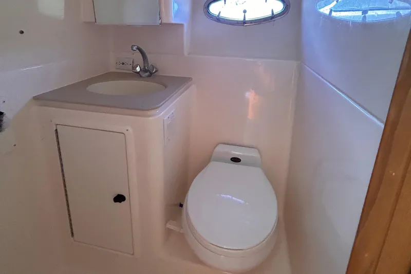 Slide: The Image of 1998 Tiara Yachts 3500 Open bathroom with sink, toilet, and porthole window. - 16