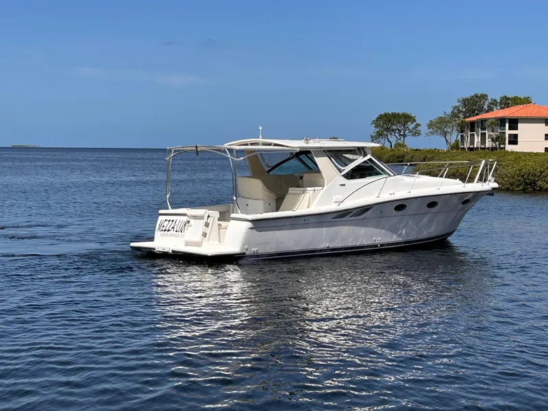 Slide: The Image of 1998 Tiara Yachts 3500 Open cruising on calm waters near a coastal home. - 6