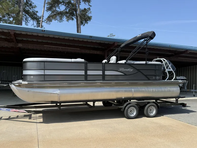Slide: The Image of 2025 Bentley Pontoons Legacy 220 Navigator on trailer, parked outdoors. - 1