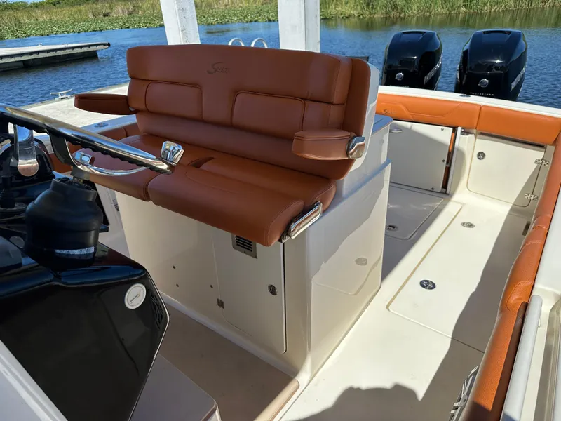 Slide: The Image of 2017 Scout 320 LXF boat interior with brown leather seating and dual outboard motors. - 13