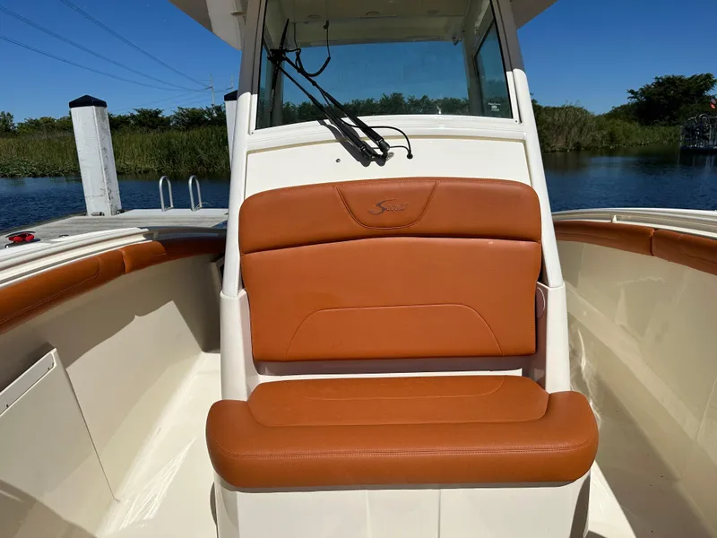 Slide: The Image of 2017 Scout 320 LXF boat with tan leather seating, docked by a serene waterway. - 16