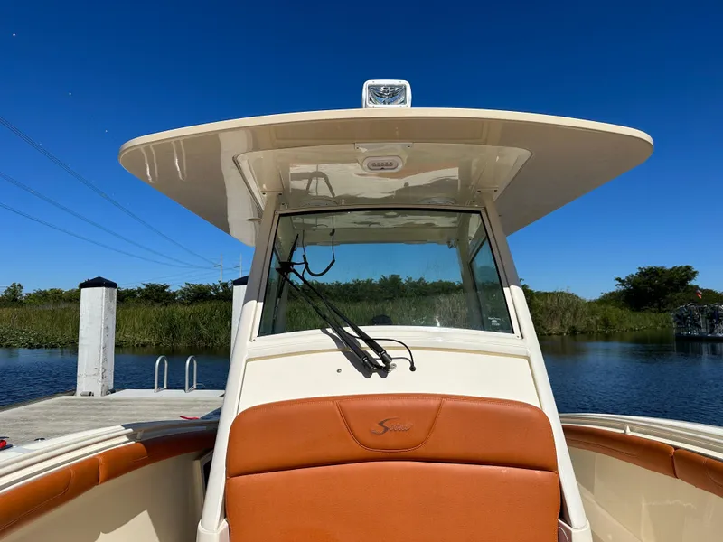 Slide: The Image of 2017 Scout 320 LXF boat docked by a serene lake under clear blue skies. - 17