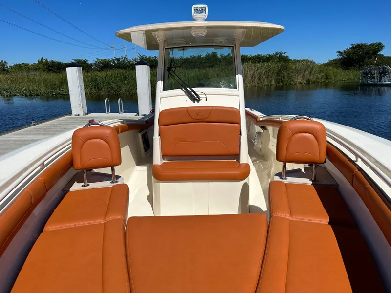 Slide: The Image of 2017 Scout 320 LXF boat with orange seating, docked by a serene waterway. - 19