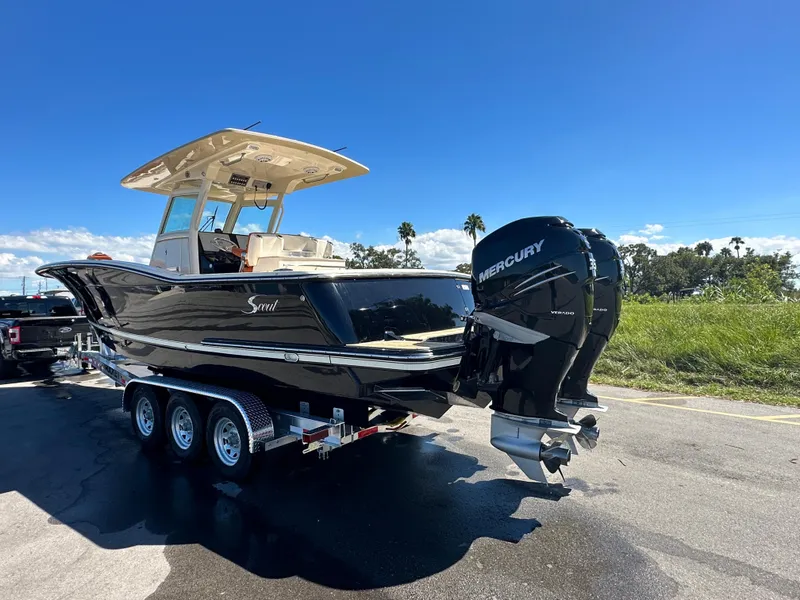 Slide: The Image of 2017 Scout 320 LXF boat with dual Mercury engines on a trailer, under clear blue sky. - 2