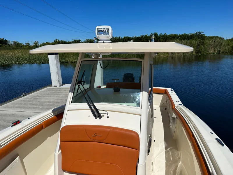 Slide: The Image of 2017 Scout 320 LXF boat docked on a sunny day, showcasing sleek design and spacious deck. - 22
