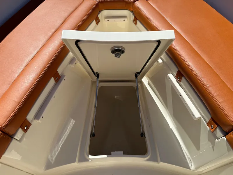 Slide: The Image of 2017 Scout 320 LXF boat storage compartment with open hatch and brown leather seating. - 26
