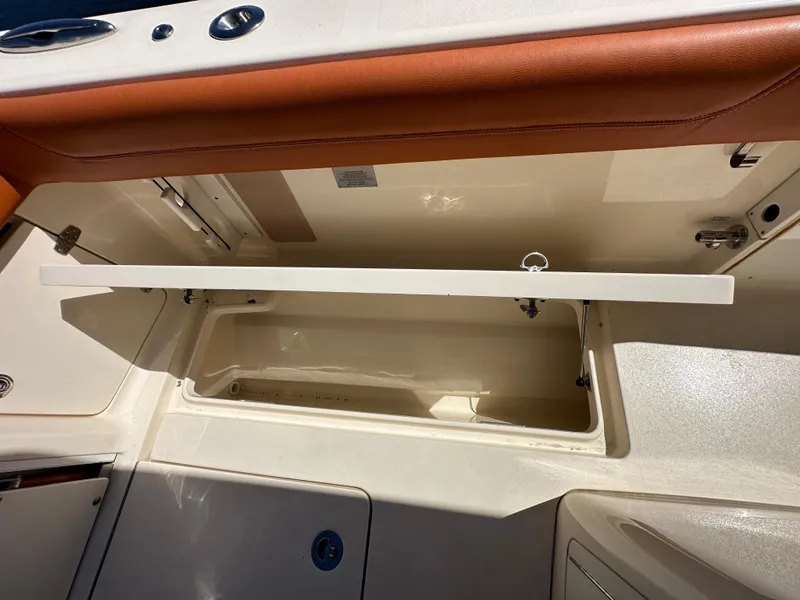 Slide: The Image of 2017 Scout 320 LXF boat storage compartment with open lid, showcasing interior space. - 35