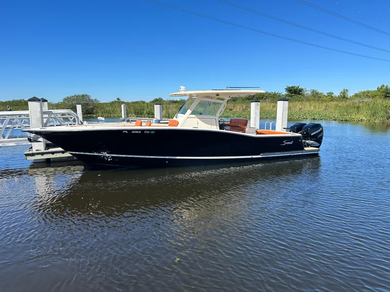 Slide: The Image of 2017 Scout 320 LXF boat docked on calm water under clear blue sky. - 4