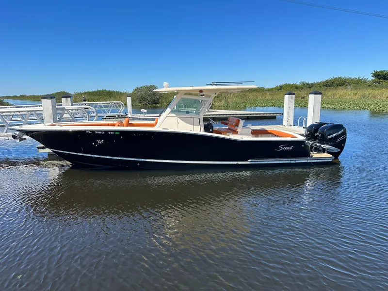 Slide: The Image of 2017 Scout 320 LXF boat docked on calm water under clear blue sky. - 5