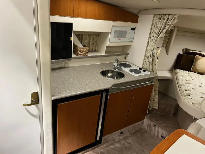 Slide: The Image of 2000 Formula 31 PC yacht interior with kitchenette, featuring sink, microwave, and cozy seating area. - 16