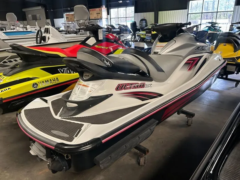 Slide: The Image of 2011 Kawasaki Jet Ski Ultra LX in showroom, white with red accents, side view. - 2