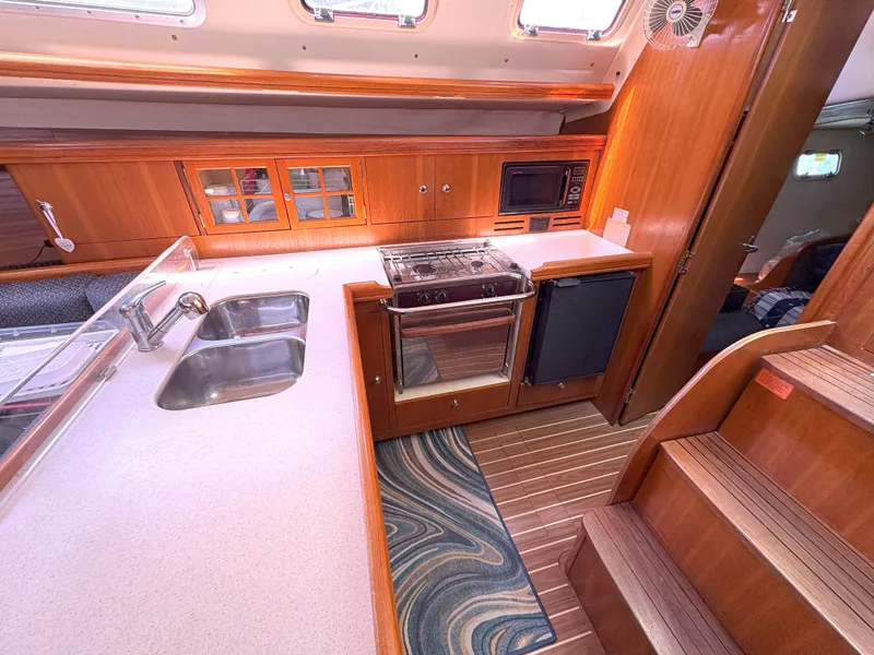 Slide: The Image of 2005 Hunter 38 yacht kitchen with wood cabinetry, dual sink, stove, and microwave. - 18