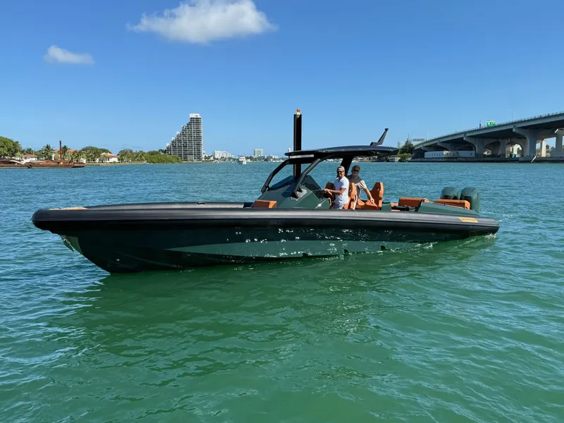 Slide: The Image of 2025 Skipper-BSK 38 boat cruising on a sunny day near a bridge and cityscape. - 3