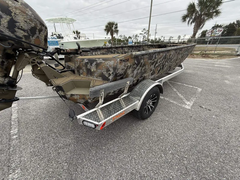 Slide: The Image of 2025 Thor Lake Hammer 1754 Timber Hammer boat on trailer, camouflage design, parked outdoors. - 8