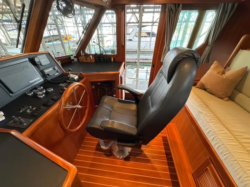 Slide: The Image of Pilothouse interior of 2010 North Pacific 43, featuring helm, leather chair, and wood finish. - 12