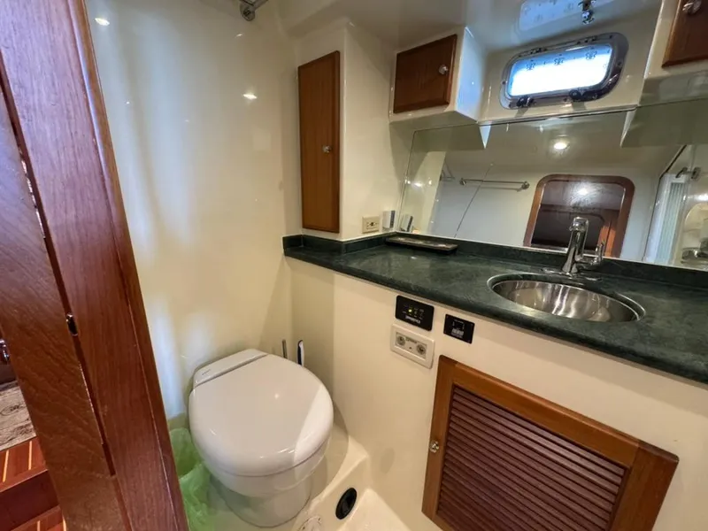 Slide: The Image of 2010 North Pacific 43 Pilothouse bathroom with sink, toilet, and storage cabinets. - 21