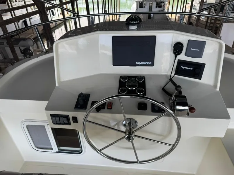 Slide: The Image of Pilothouse of 2010 North Pacific 43, featuring steering wheel and Raymarine navigation equipment. - 26
