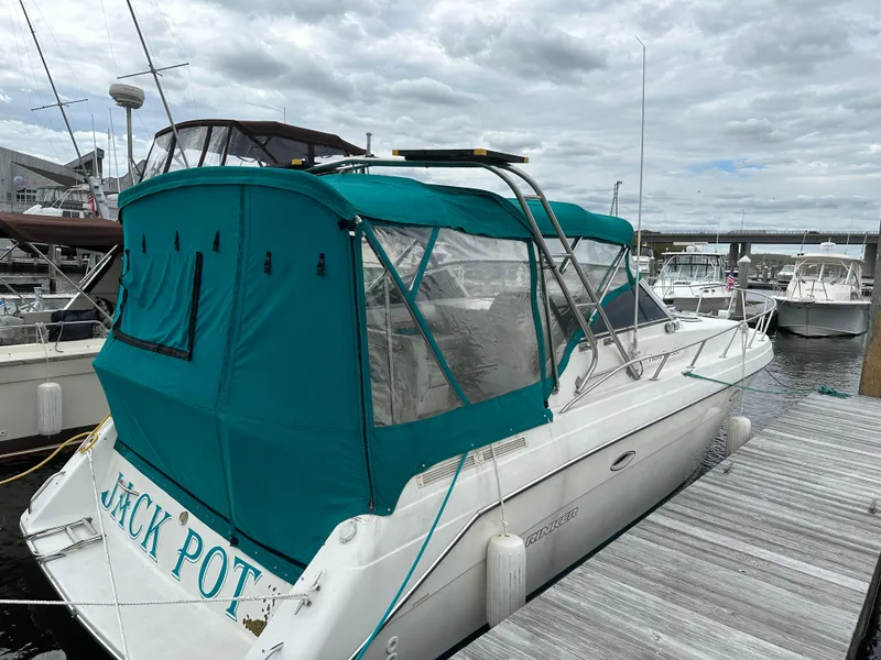 Slide: The Image of 1996 Rinker 300 Fiesta Vee boat docked with teal canopy and clear windows. - 0