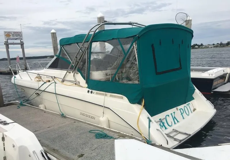 Slide: The Image of 1996 Rinker 300 Fiesta Vee boat docked with green canopy, calm waters in background. - 1