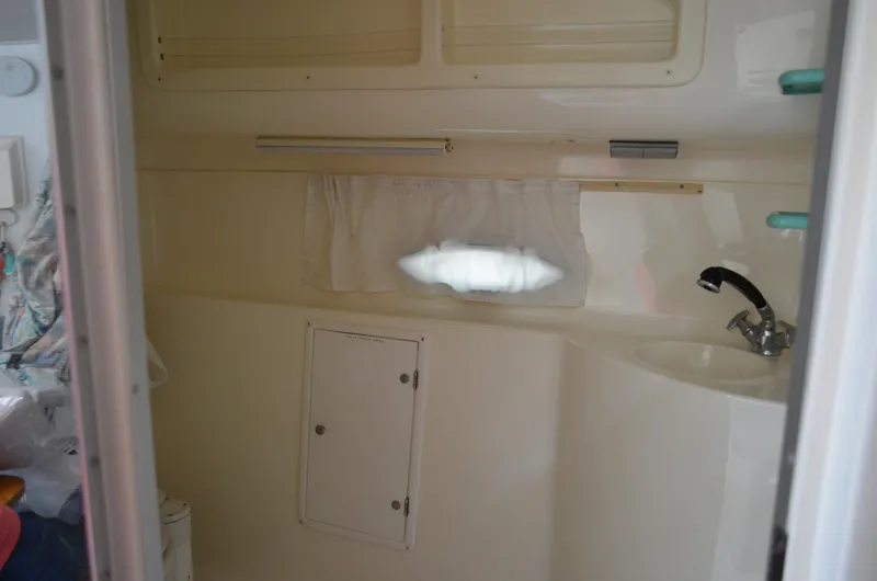 Slide: The Image of Interior of a 1996 Rinker 300 Fiesta Vee boat bathroom with sink and storage. - 48