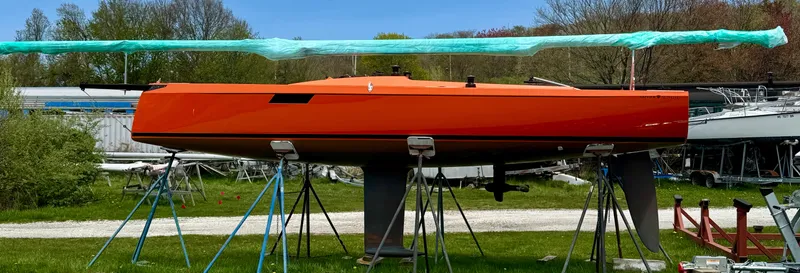 The Image of 2025 Saffier 24 Lite sailboat in vibrant orange on stands, surrounded by greenery. - 0