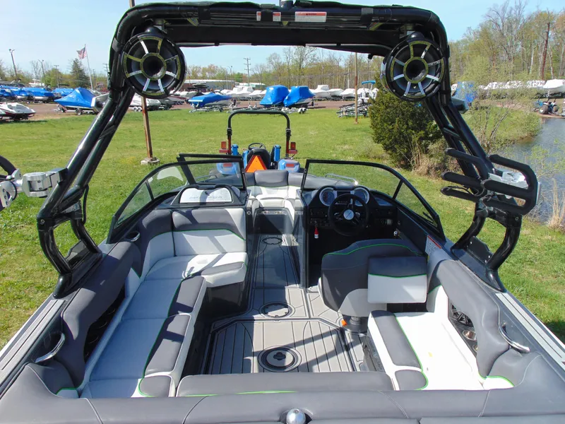 Slide: The Image of 2018 Moomba Mondo boat interior with seating and speakers, parked on grass near water. - 15