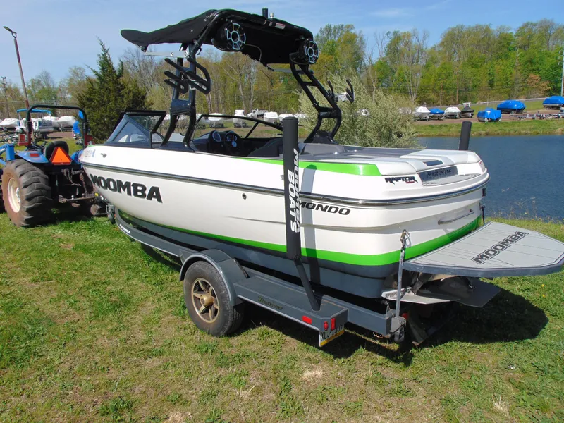 Slide: The Image of 2018 Moomba Mondo boat on trailer by a lake, featuring green accents. - 7