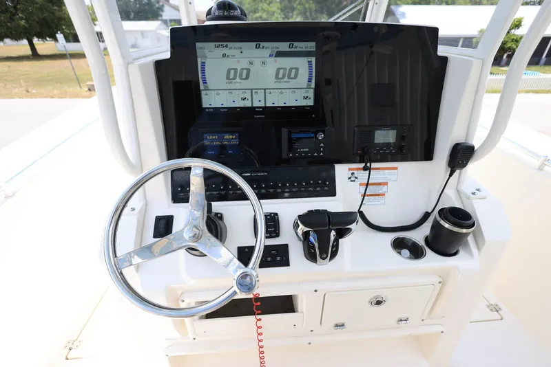 Slide: The Image of 2022 Cobia 301 Center Console boat dashboard with steering wheel and electronic controls. - 12