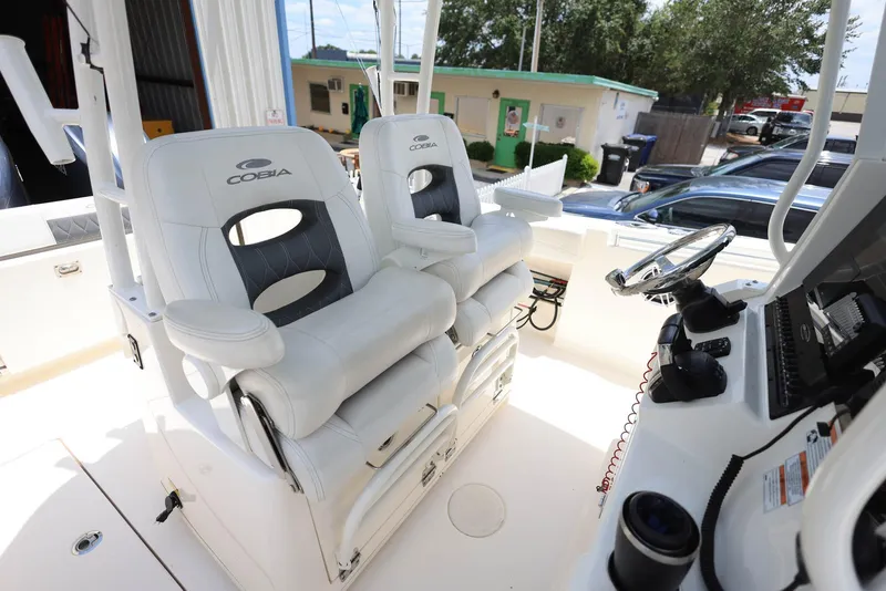 Slide: The Image of 2022 Cobia 301 Center Console boat with dual white captain's chairs and control panel. - 23