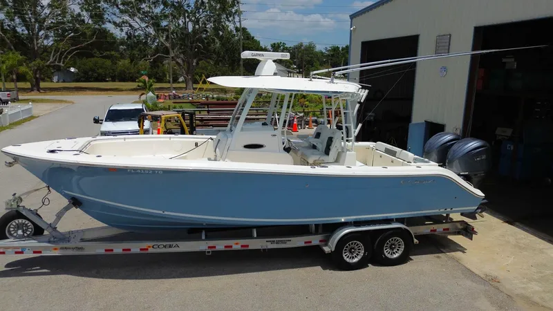 Slide: The Image of 2022 Cobia 301 Center Console boat on trailer outside a garage. - 25